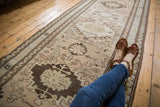 Distressed Persian Serab runner's geometric medallion in beige, brown, and pale blue, with mostly even low pile.