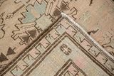Distressed Serab runner's folded corner, featuring worn low pile and geometric beige, pale blue, brown pattern.