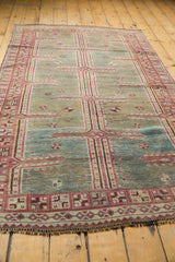 Distressed Oushak rug detail with faded raspberry and blue maze pattern.