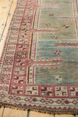 Distressed vintage Oushak runner detail showing faded raspberry, teal, and beige geometric patterns.