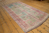 Corner of distressed Oushak runner with raspberry, ivory border and sky blue maze pattern.