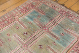 Distressed Oushak rug detail showing faded raspberry, sky blue, and ivory maze pattern.