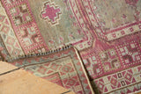 Distressed Oushak rug detail: raspberry, sky blue, ivory geometric pattern, visible worn texture.