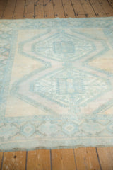 Secured end of distressed vintage Afshar rug, faint foundation through pale blue motifs.
