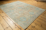 Faded ivory, sky blue, and peach geometric pattern on a distressed vintage Afshar rug.