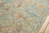 Close-up of distressed Afshar rug border with faded sky blue, ivory, and peach geometric patterns.