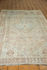 Distressed vintage Shiraz rug corner with faded sky blue and peach geometric patterns.