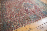 Distressed vintage Karaja rug with geometric vinery patterns in brick red, teal, and ivory.