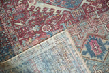 Corner of distressed Karaja rug showing brick red, teal geometric pile, hand-knotted back, and fringe.