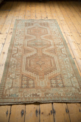 Close-up of a distressed Serab runner's secured end, with worn geometric patterns in neutral and seafoam tones.