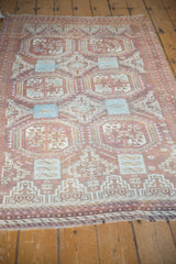 Distressed Belouch rug with faded cranberry and powder blue geometric guls, rams horn motifs, and low pile.