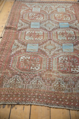 Textured, distressed Belouch rug showing worn floral guls in faded cranberry and pale blue.