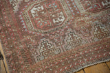 Distressed Belouch rug corner with faded cranberry and blue geometric guls, stepped border.