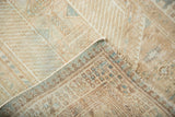Folded vintage distressed Serab rug shows textured pile with visible foundation and geometric reverse.