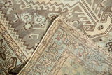 Folded corner of a distressed vintage Shiraz rug, revealing geometric patterns and hand-knotted backing.