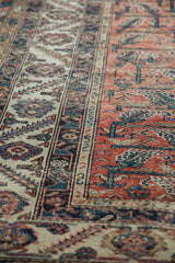 Vintage Malayer rug with intricate ivory border, terracotta field, floral vinery, and visible wear.
