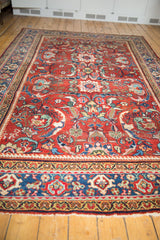 Detail of vintage Mahal carpet's indigo blue border, cherry red scrolling field, and secured fringe.