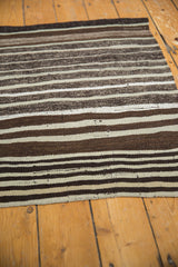 Textured vintage Moroccan Kilim showing striated horizontal bands in shades of brown and ivory.