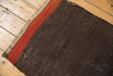 Vintage Turkish Kilim rug corner with textural fringe and distinct charcoal, brick red stripes.