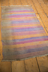2x4 Vintage Distressed Turkish Kilim Rug Runner with faded horizontal stripes in soft orange, purple, and beige tones, showing subtle wear and aged texture