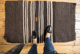 Alternating charcoal and ivory stripes of a vintage Turkish Kilim with orange embroidered detail.