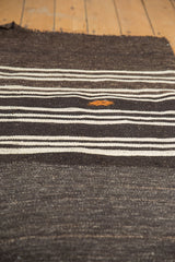 Charcoal and ivory striped vintage Turkish Kilim rug with orange embroidered detail.