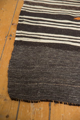 Vintage Turkish Kilim corner with charcoal and ivory stripes, natural weave, and dark fringe.