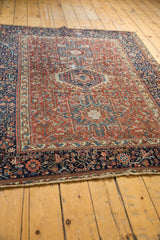 Angled view of a vintage Karaja rug corner showing the geometric navy border and red field.