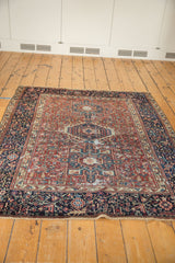 Angled view of a hand-knotted vintage Karaja rug with a geometric red and navy blue pattern.