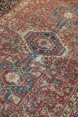 Detail of a vintage Karaja rug's geometric medallion showing time-softened pile in red and indigo blue.