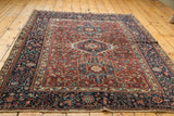 Intricate navy blue geometric border against the deep red field of the Karaja rug.