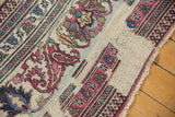 Distressed antique Khorassan carpet detail: worn fuscia and blue floral motifs on exposed foundation.