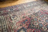 Distressed antique Khorassan rug corner, revealing Laleh Abassi pawn border and faded fuscia, blue floral motifs.