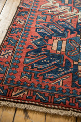 Angular brick red and navy geometric patterns on vintage Karaja rug with fringe.