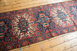 Close-up of hand-knotted geometric patterns in brick red, navy, and ivory on vintage Karaja runner.