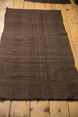 Secured end and rich chocolate brown texture of a vintage Turkish Kilim rug.