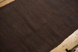 Close-up of hand woven dark brown Turkish Kilim showing subtle warp and weft texture.