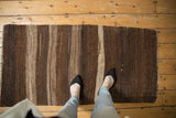 Striated abrashes and varying stripes in dark brown and ivory on a hand-woven Kilim.