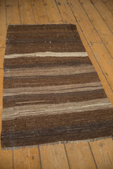 Textured flat weave Turkish kilim rug with striated brown and ivory horizontal bands.