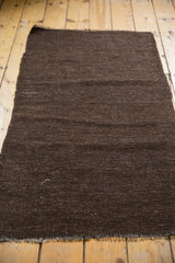 Secured side edge and speckled dark chocolate brown weave of the Turkish Kilim rug.