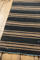 Charcoal and khaki stripes on a hand woven Turkish Kilim rug, light blue edge.