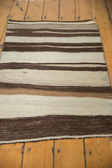 Secured end of the vintage Turkish Kilim showing striated ivory and dark chocolate stripes.