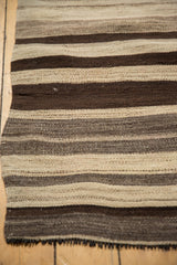 Close-up of vintage Turkish Kilim rug showing hand-woven striated ivory and brown stripes and fringe.