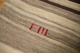 Hand woven Turkish Kilim texture with striated coffee brown bands and a unique red insignia.