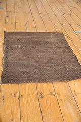 Hand woven coffee brown striations along the vintage Turkish Kilim rug's secure edge.