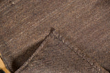 Close-up of hand woven brown Kilim texture with ivory striations and folded edge.