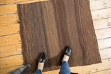 Subtly striped texture of a vintage Turkish Kilim rug in charcoal brown and beige.