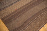 Vintage hand-woven Turkish Kilim texture, showing subtle charcoal brown striations and a small red thread.