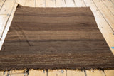 Natural brown and beige striations on a hand-woven Turkish Kilim, with fringe and red detail.