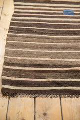 Hand-woven Moroccan kilim's striped pattern with varied charcoal brown, beige, and blue patch.